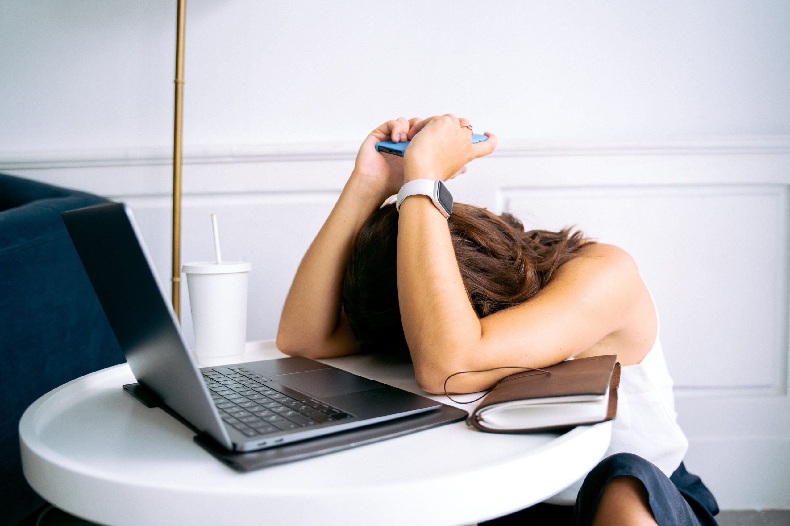 Woman looking stressed while juggling a laptop and smartphone, illustrating the overwhelm of app-based dating.