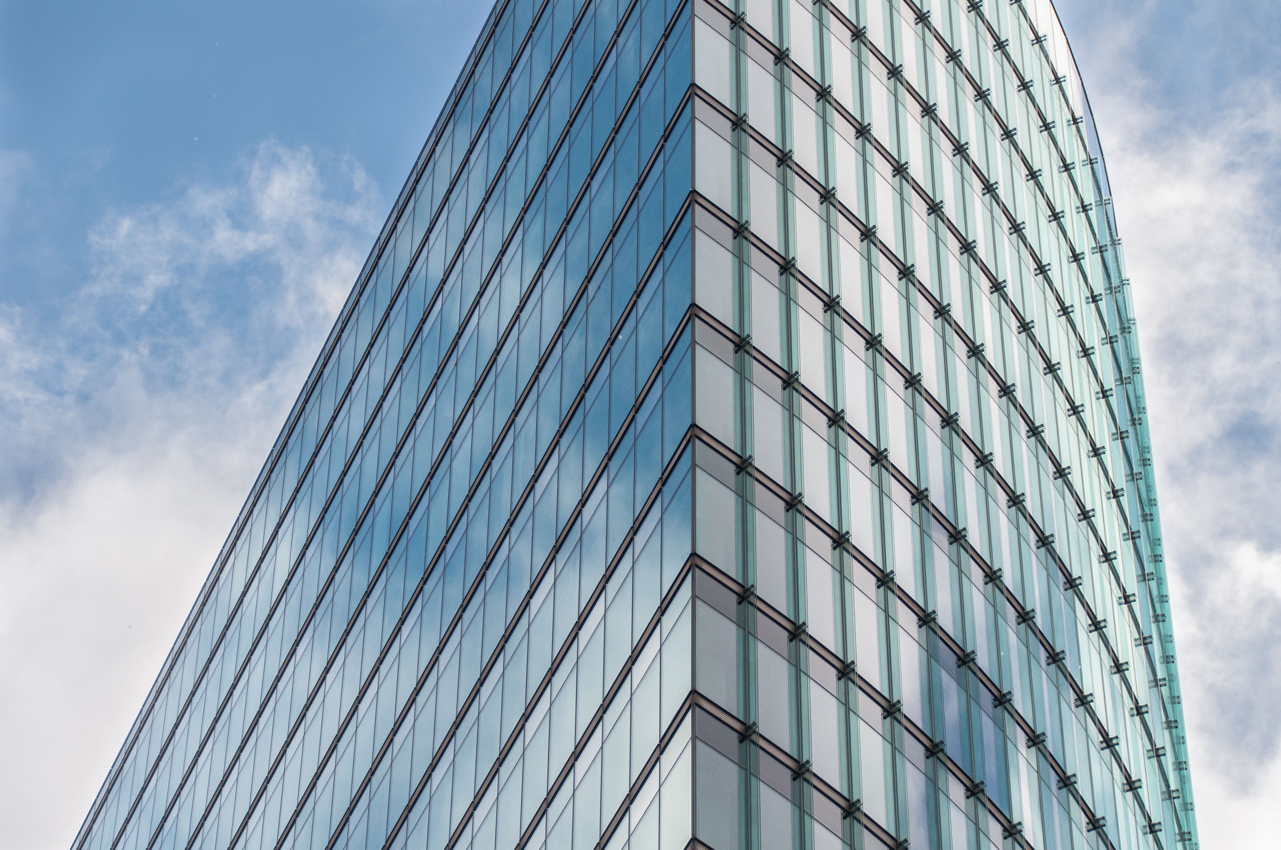 Sleek glass skyscraper reflecting the sky, representing international law firm offices worldwide