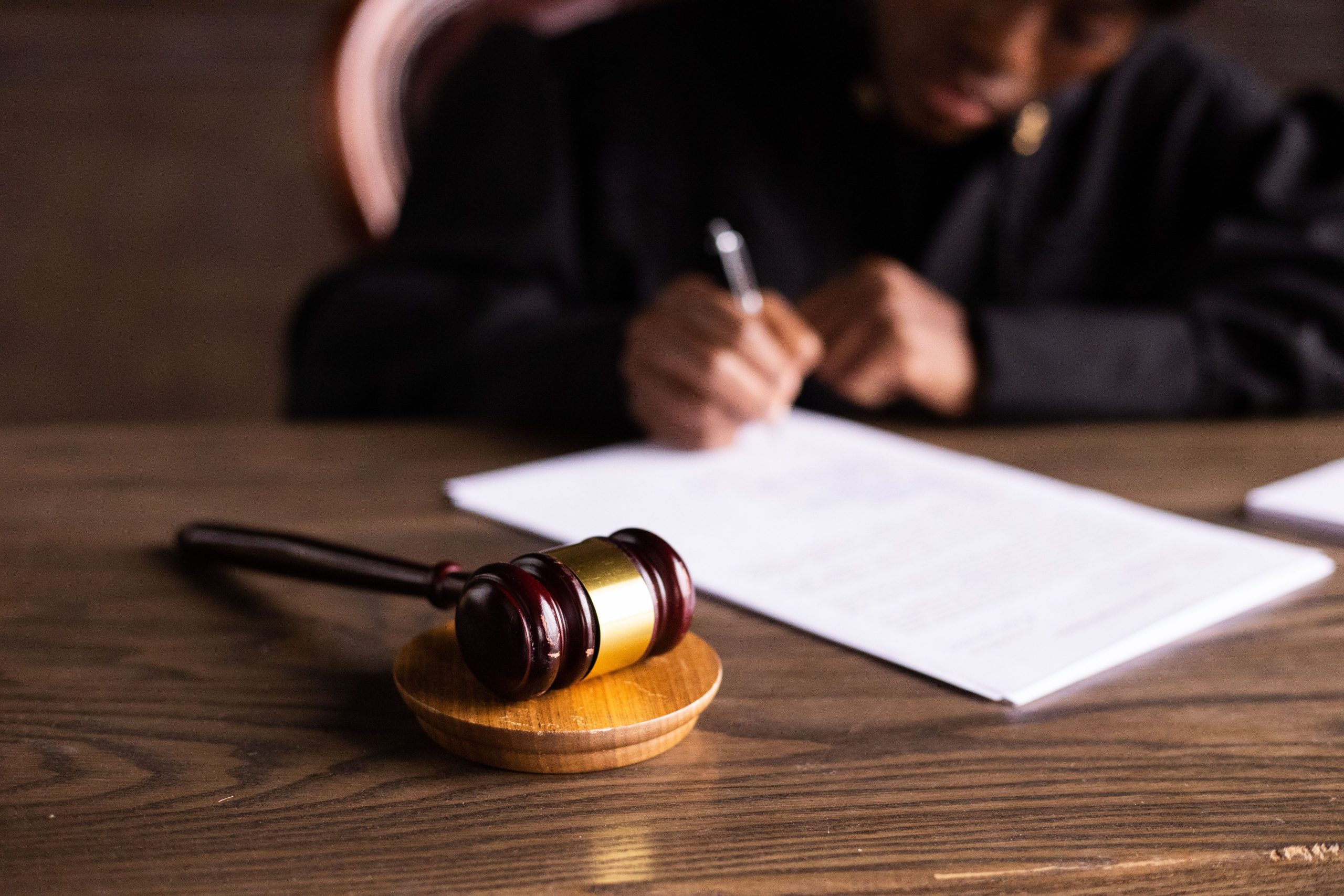 Judge signing documents at a desk with a gavel in focus, representing law and justice