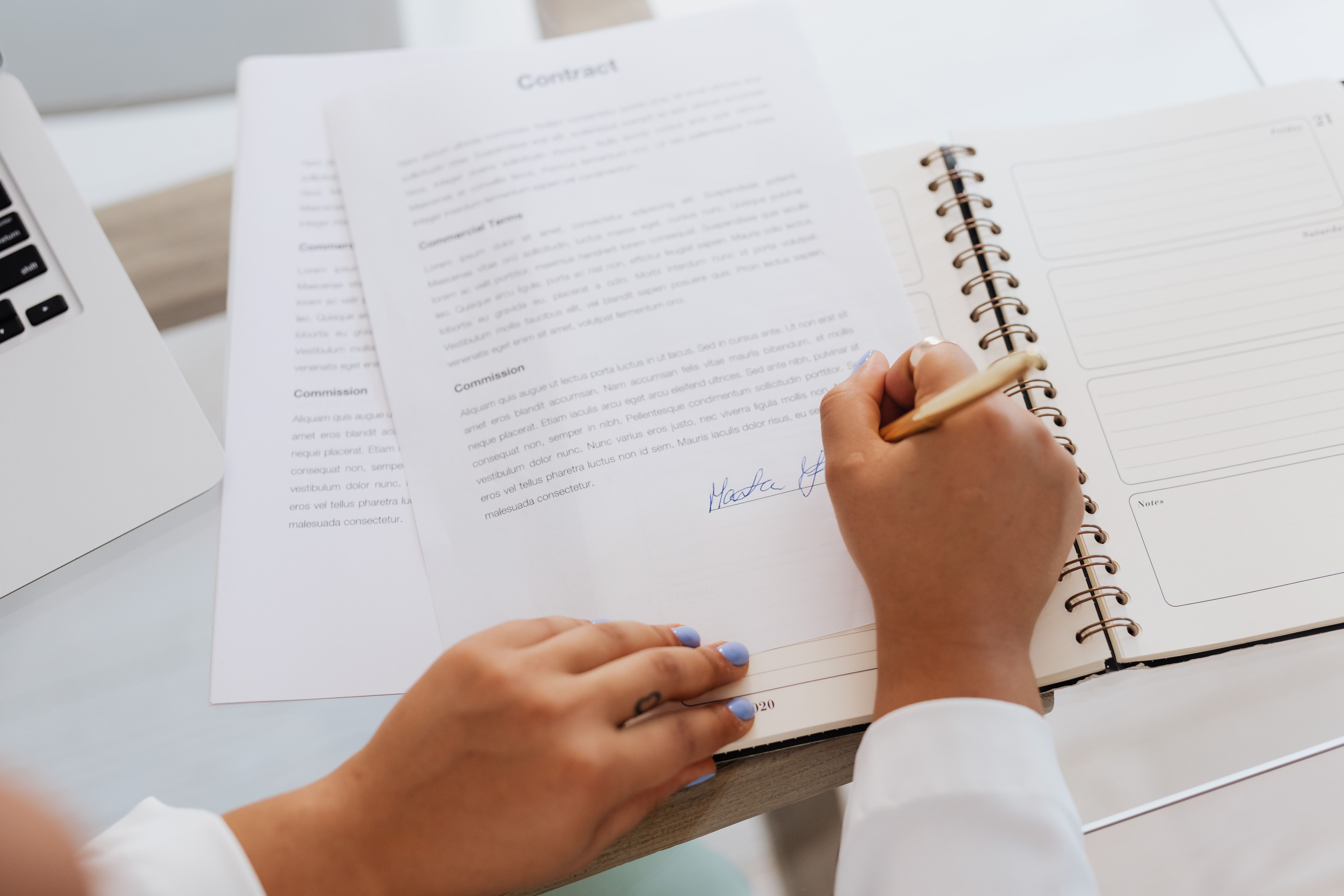 Close-up of hands signing a contract on a desk symbolizing international legal agreements