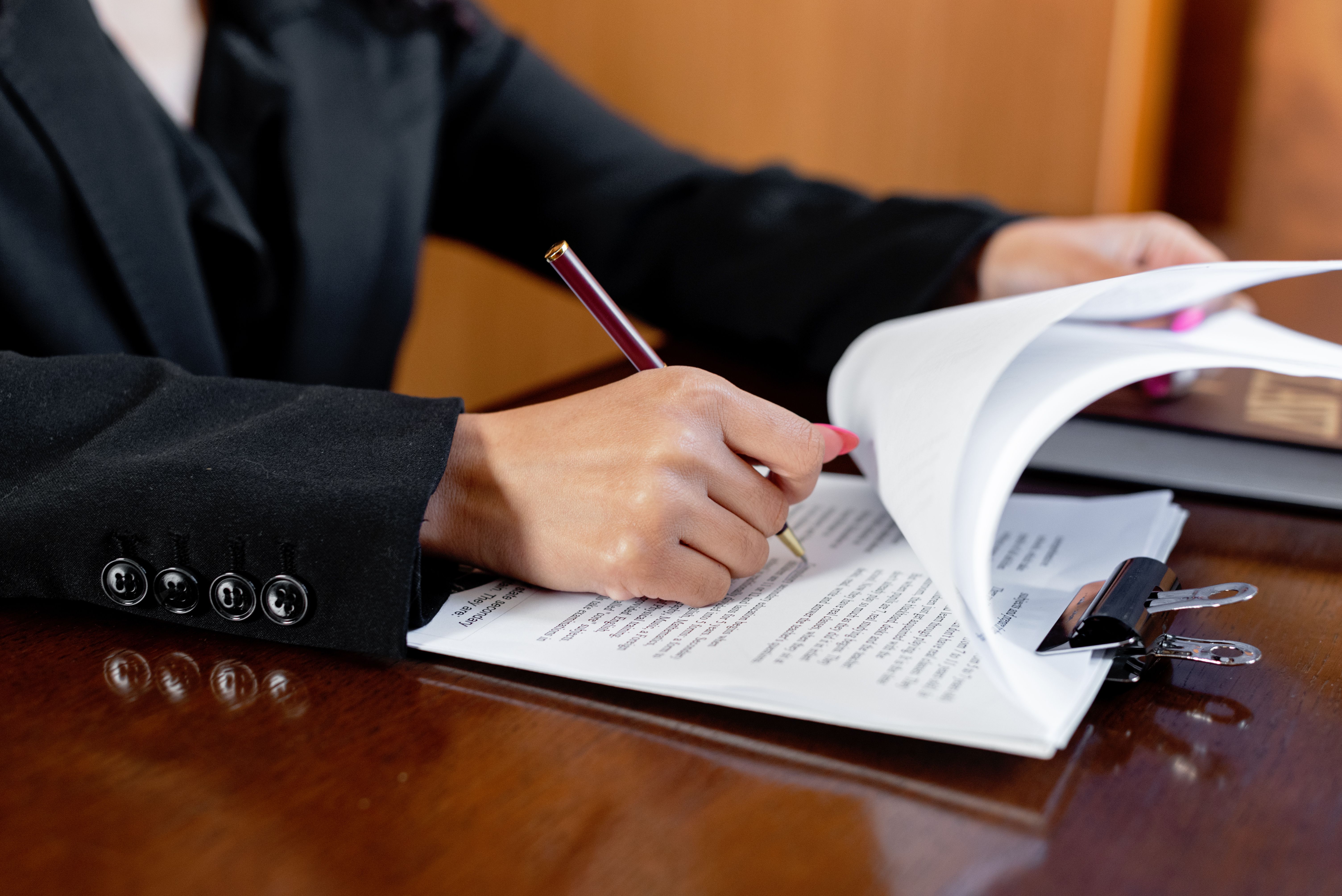Close-up of a woman signing legal documents with a pen